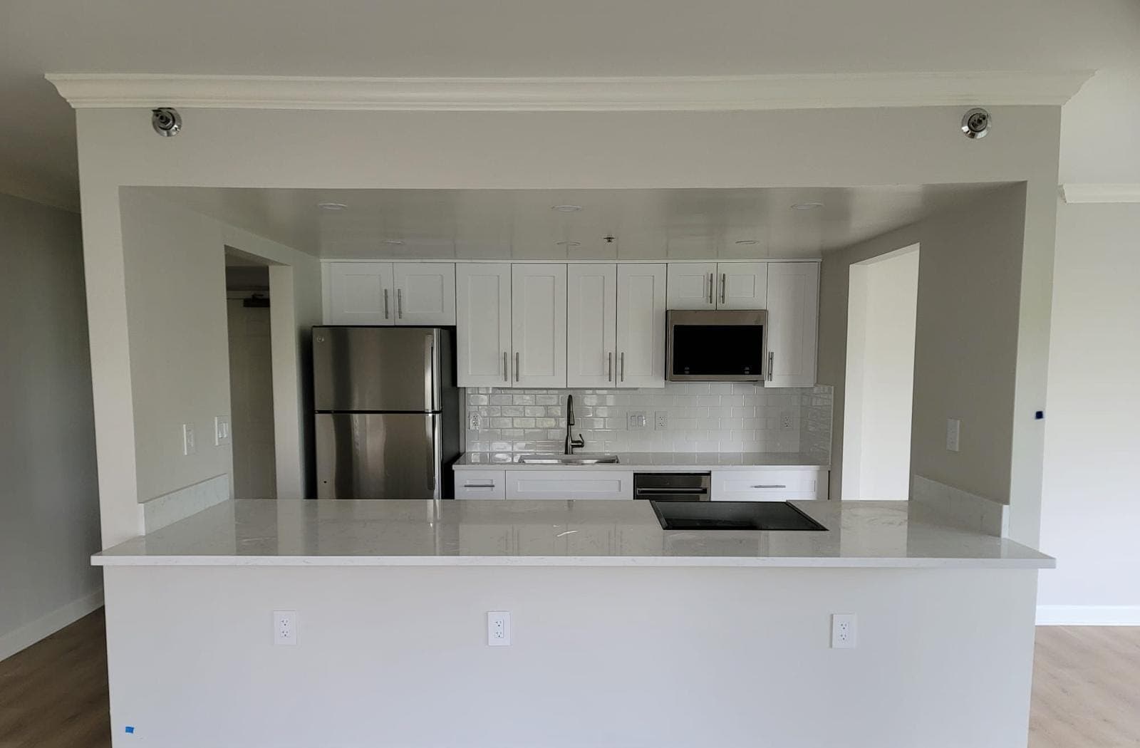 Remodeled kitchen with white shaker cabinets and quartz peninsula